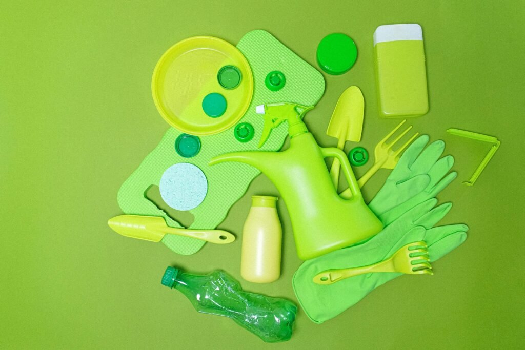 Top view monochrome of various plastic bottles and kitchen utensil polluting planet on green background, showing the need for plastic waste management