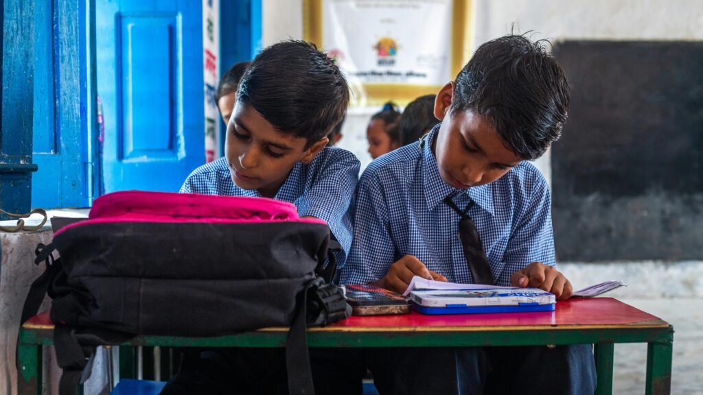 Two boys are sitting at a desk with books representing climate change education