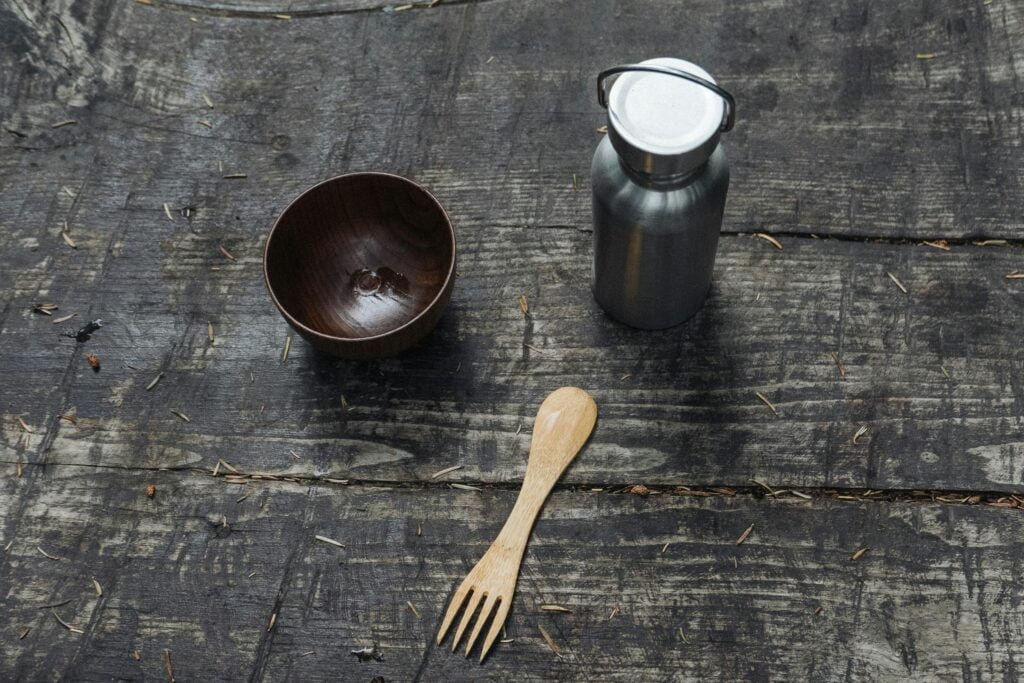 A Wooden Bowl and Fork Near the Stainless Tumbler representing zero- waste living