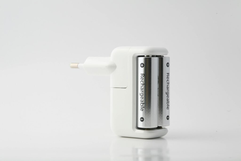 Minimalist shot of a rechargeable battery charger with two batteries on a white backdrop.