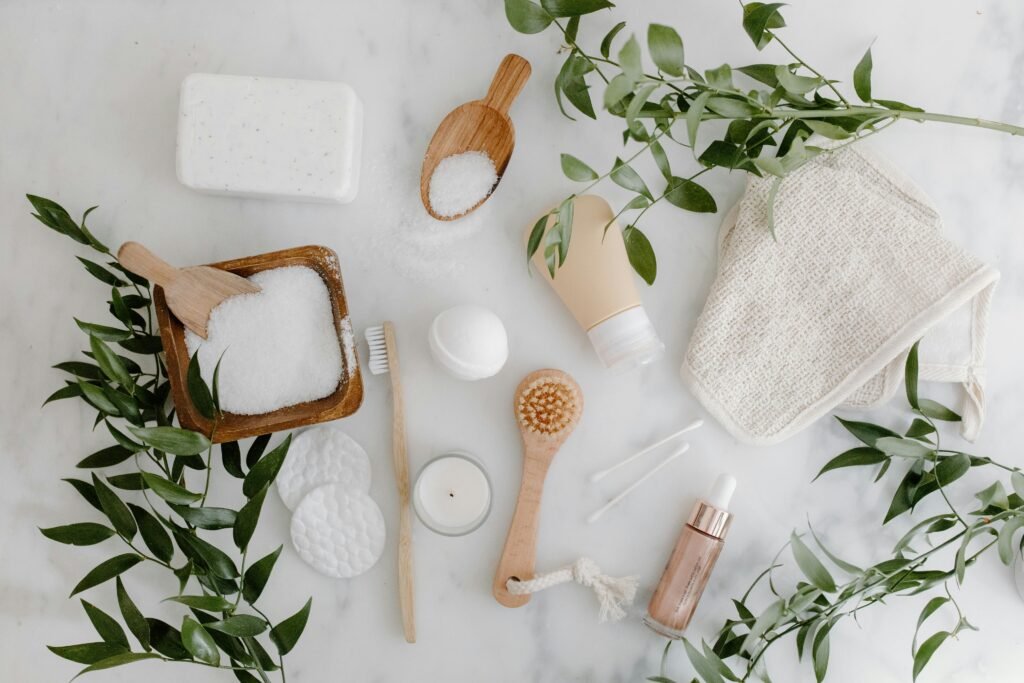 Elegant flat lay of organic bath essentials including soap, brush, and salts with greenery. eco-friendly home products.