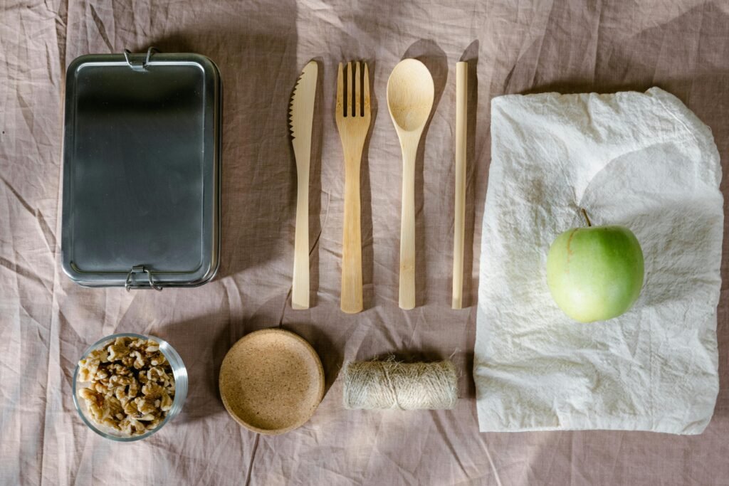 A flat lay of eco-friendly lunch items including wooden cutlery and a green apple. for eco-friendly morning routine.