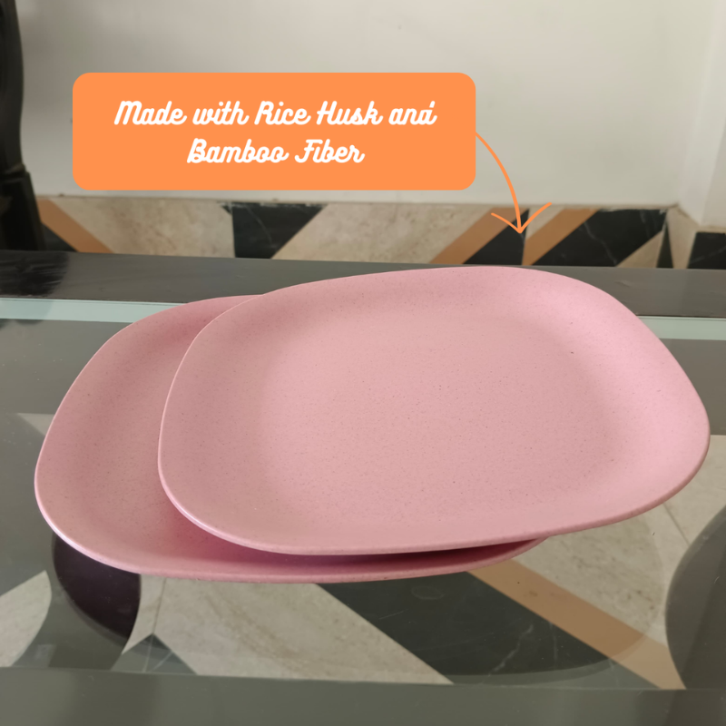 2 pink plates kept on glass table with made with rice husk and bamboo fiber written in orange text box